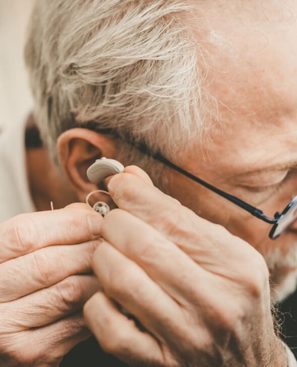 An Elderly Gentleman Putting on his Hearing Aid Device